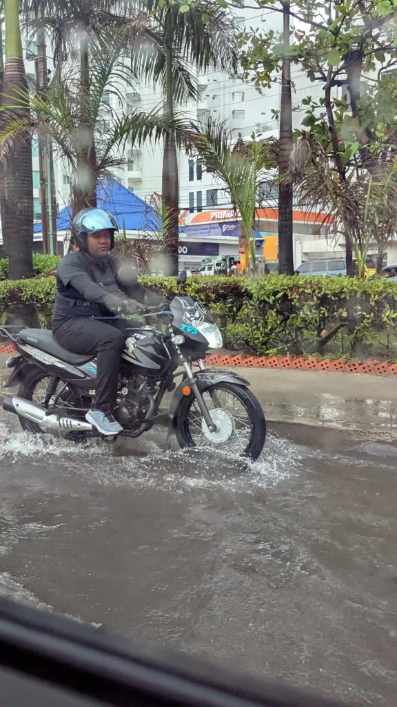 Ein Rollerfahrer fährt durch das Knöcheltiefe Wasser das nach einem Starkregen in den Straßen steht.